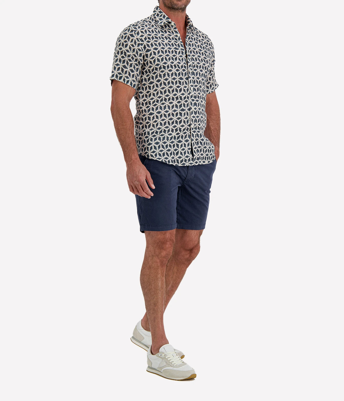 Man wearing Osvaldo Trucchi Linen Short Sleeve Shirt in Navy Geo Star Print with navy shorts and white sneakers, front view with hand in pocket