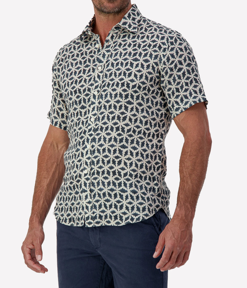 Man wearing Osvaldo Trucchi Linen Short Sleeve Shirt in Navy Geo Star Print with navy shorts, cropped three-quarter view