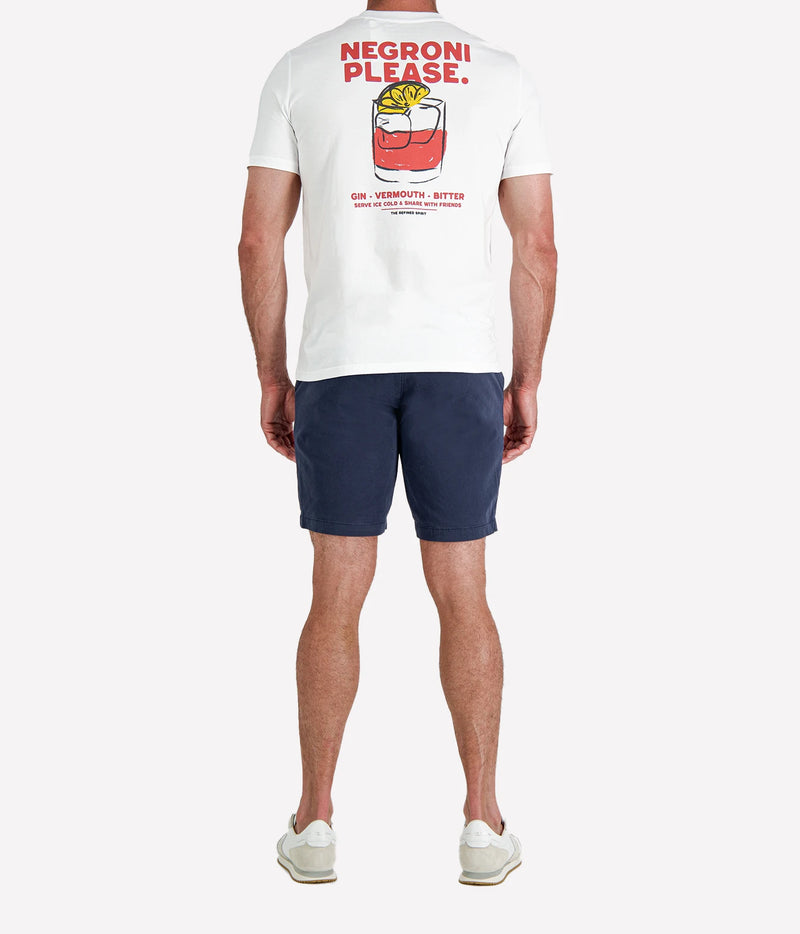 Back view of man wearing The Refined Spirit Negroni Please Tee in White with navy shorts and white sneakers