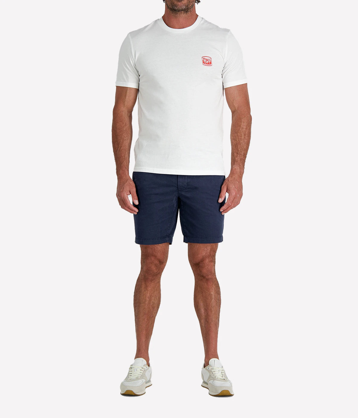 Man wearing The Refined Spirit Negroni Cocktail Bar Tee in White with navy shorts and white sneakers, full-length front view