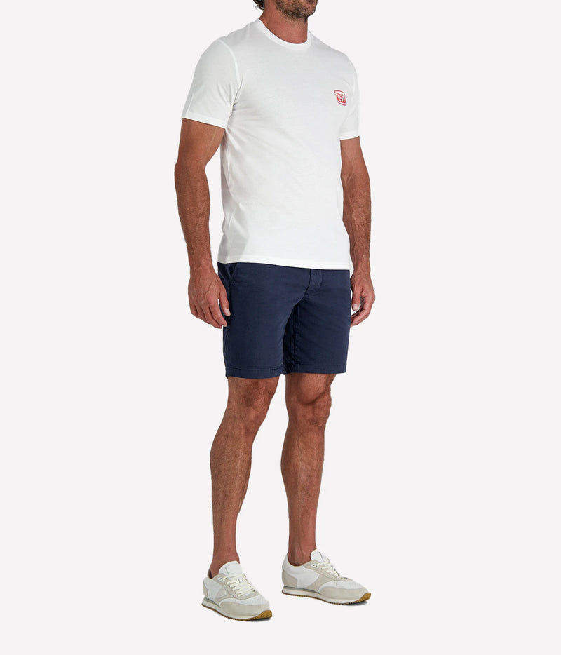 Man wearing The Refined Spirit Negroni Cocktail Bar Tee in White with navy shorts and white sneakers, three-quarter view