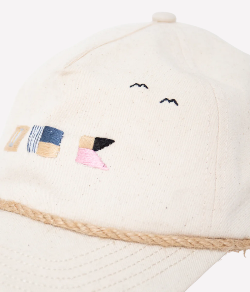 Nick Fouquet sailing flags cap – natural cotton twill with embroidered sailing flags and birds, brown leather strap, and braided rope detail.