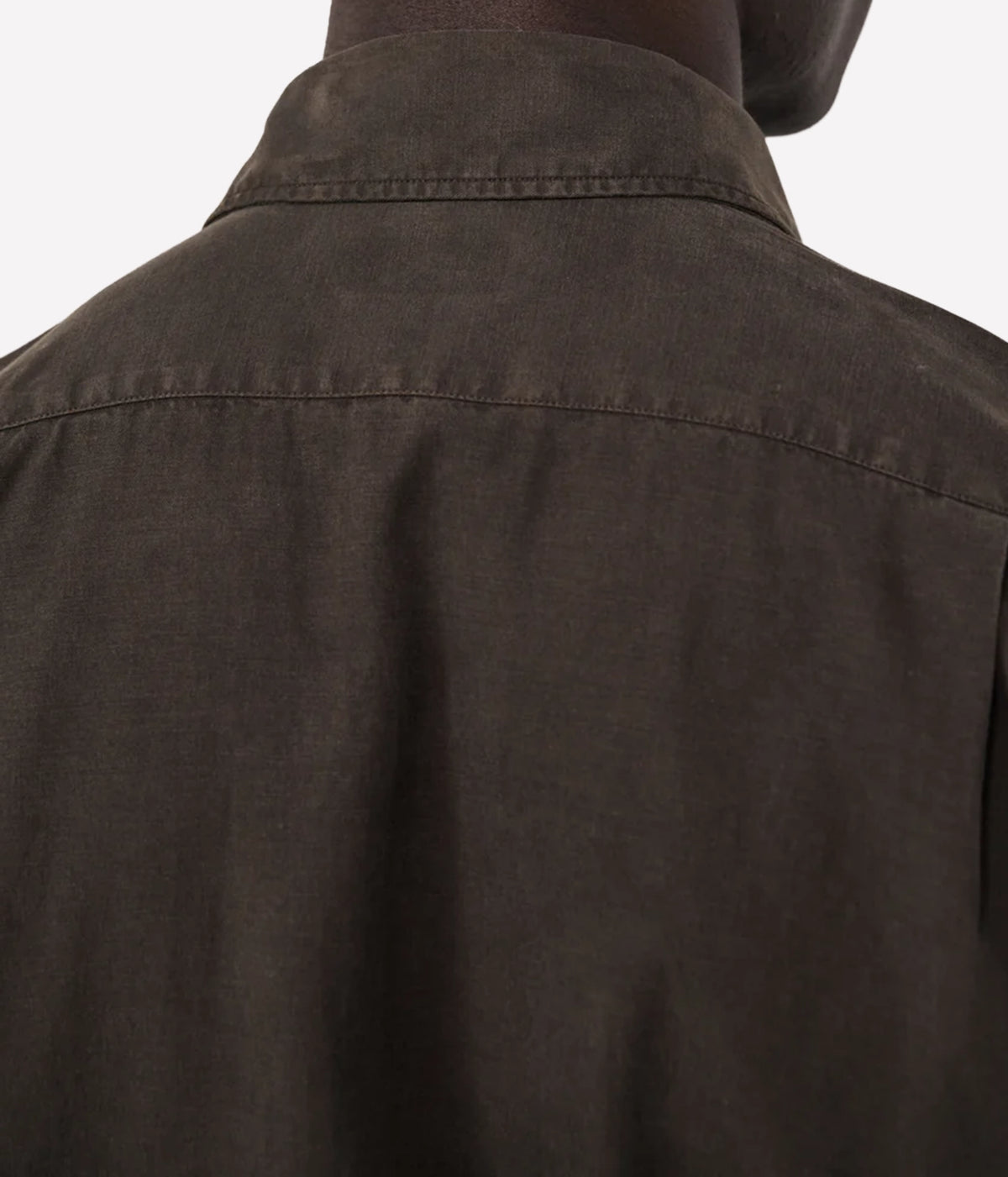 Close-up back view of a person wearing a dark brown collared shirt or jacket against a plain light background.