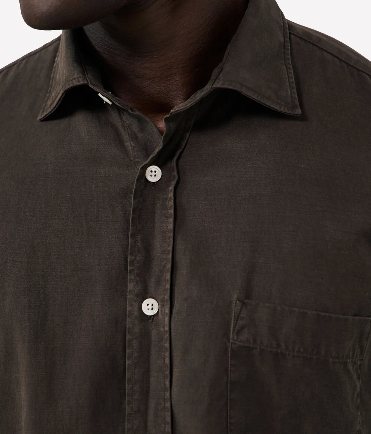 Close-up of a dark brown button-down shirt worn by a model, showing the collar, front buttons, and chest pocket.