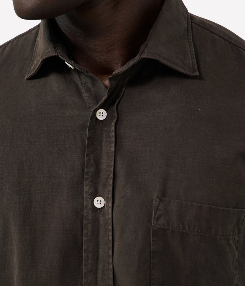 Close-up of a dark brown button-down shirt worn by a model, showing the collar, front buttons, and chest pocket.