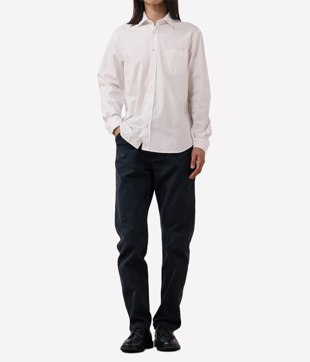 A model wearing a white long-sleeve button-down shirt and dark navy pants.
