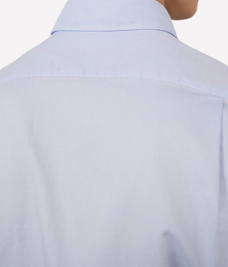 Close-up back view of a light blue button-down shirt worn by a model, showing the collar and upper back fabric.