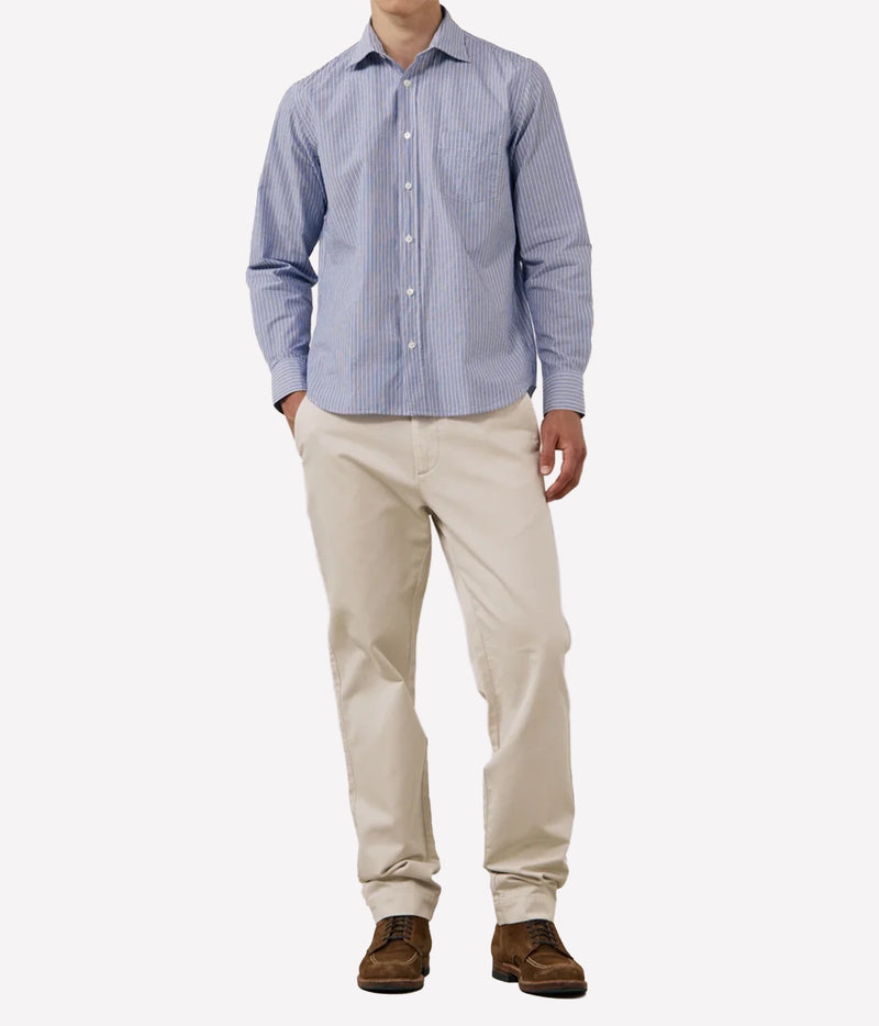 A man wearing a light blue and white vertically striped long-sleeve button-down shirt, beige trousers, and brown suede shoes, shown from the neck down.