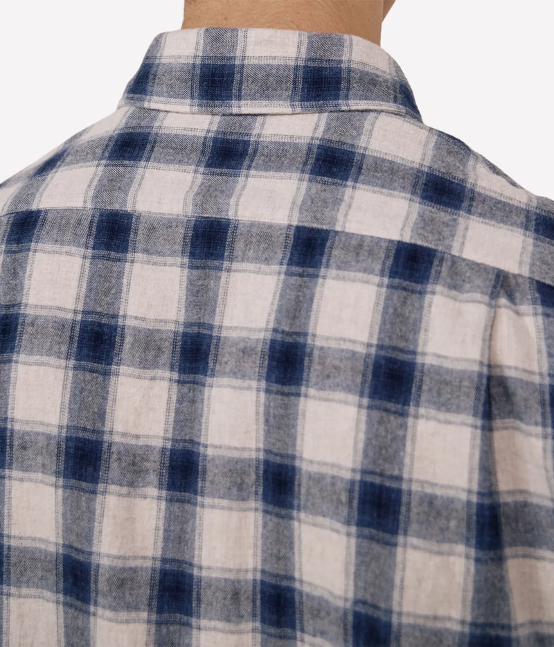 Close-up of the back of a plaid button-up shirt on a model, featuring a navy blue and off-white checkered pattern.