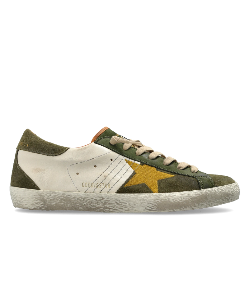 A low-top sneaker featuring an olive green suede and canvas upper, a cream leather side panel, a prominent yellow star on the side, and a thick cream rubber sole.