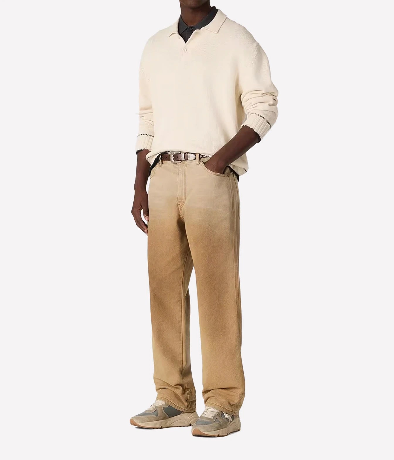 A model wearing a cream long-sleeve polo sweater, beige straight-leg corduroy trousers, a silver belt, and gray sneakers, standing against a plain white background.