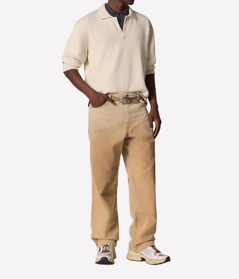 A model wearing a cream short-sleeve knit polo shirt, beige wide-leg corduroy pants, a brown belt, and white sneakers, shown against a plain light gray background.