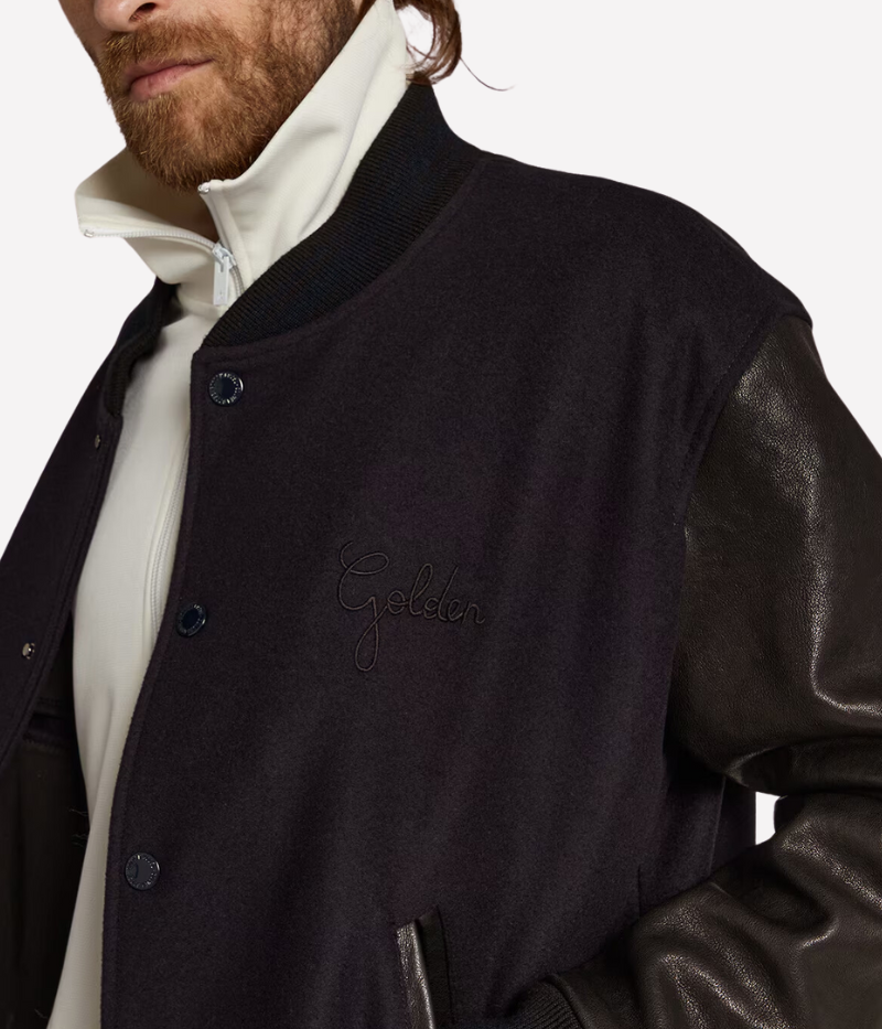 Golden Goose Golden Leather Bomber jacket in dark blue and black, featuring a wool blend body with distressed black leather sleeves and a signature double gold star detail on the back. Regular fit with button-up front, front pockets, and cotton lining for comfort. Crafted in Italy for a laid-back luxury look.