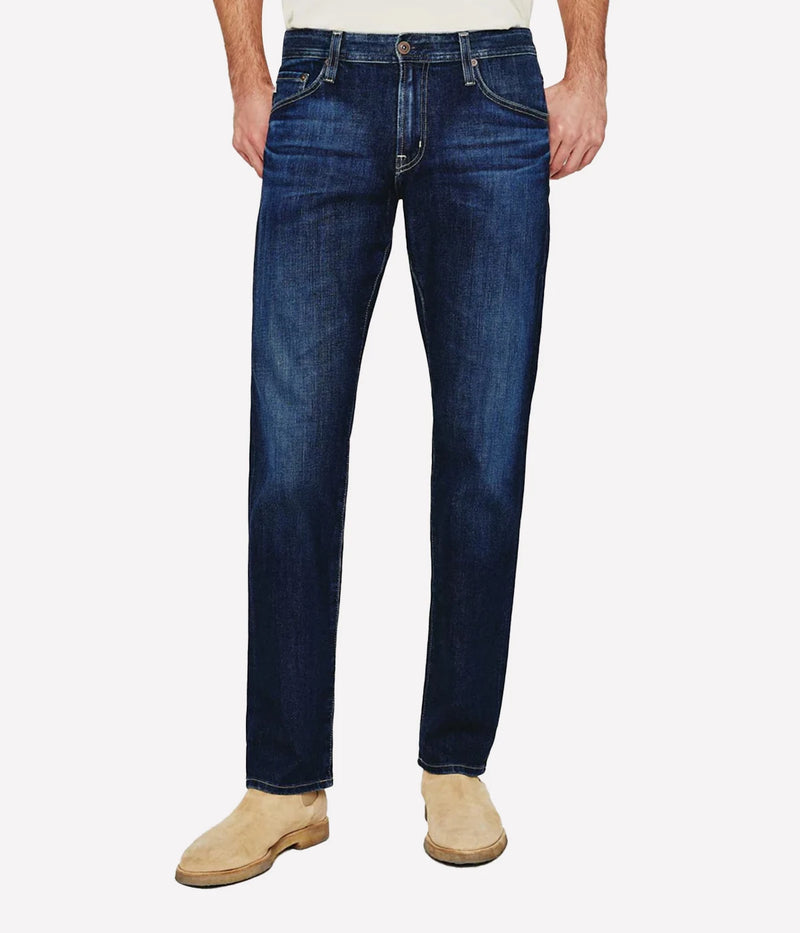AG Graduate slim straight jeans for men in a medium-dark wash, featuring a slim mid-rise waist and relaxed fit through the hip to the knee. Tapered leg opening with Flex 360° Denim for added comfort and stretch