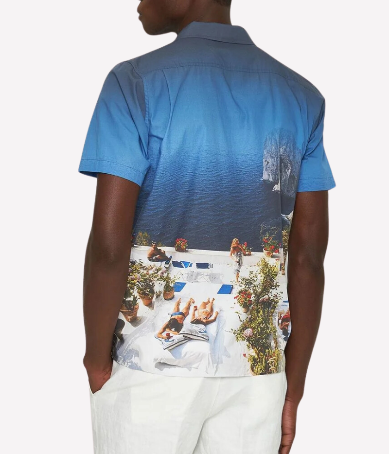 A statement short-sleeve shirt featuring an exclusive Slim Aarons photographic print of sunbathers at Villa Il Canille, a classic fit, Capri collar, and imitation mother-of-pearl buttons.