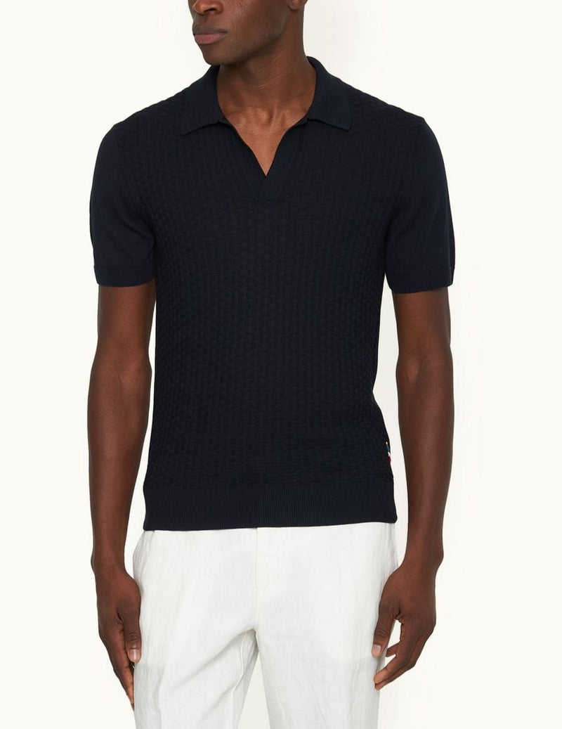 Silk-cotton blend resort-style knit with a tailored fit, featuring a short, open placket, ribbed cuffs, hem, and placket. Jacquard knit pattern with fully fashioned construction and O.B. stitch near the hem