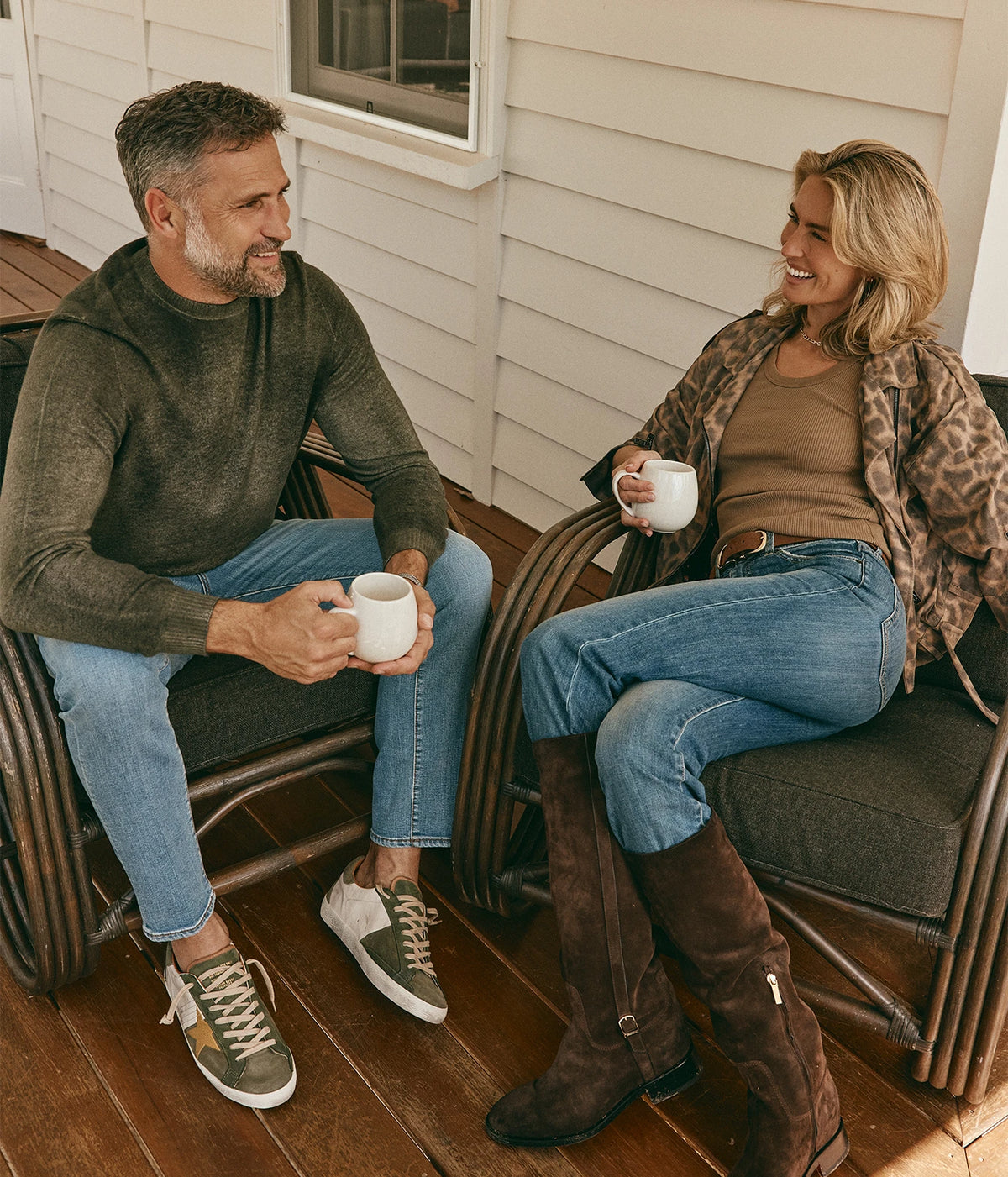 Man wearing Avant Toi Hand Painted Light Cashmere Round Neck Pullover in Moss with jeans, seated on a porch with a coffee