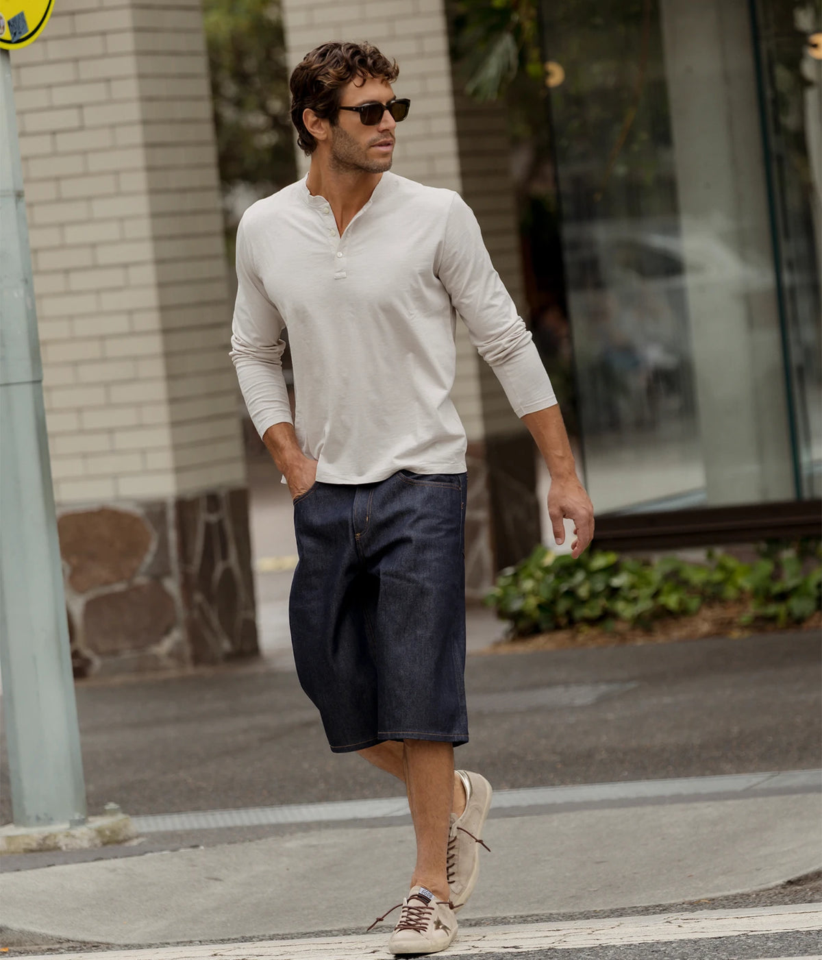 Man wearing Hartford Henley Long-Sleeve T-Shirt in Stone with navy shorts, walking on the street, full-length front view