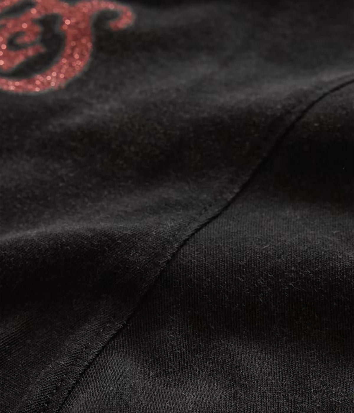 Close-up of John Varvatos The Rolling Stones NYC Raw Edge Tee in Black showing the fabric, seam and red graphic detail