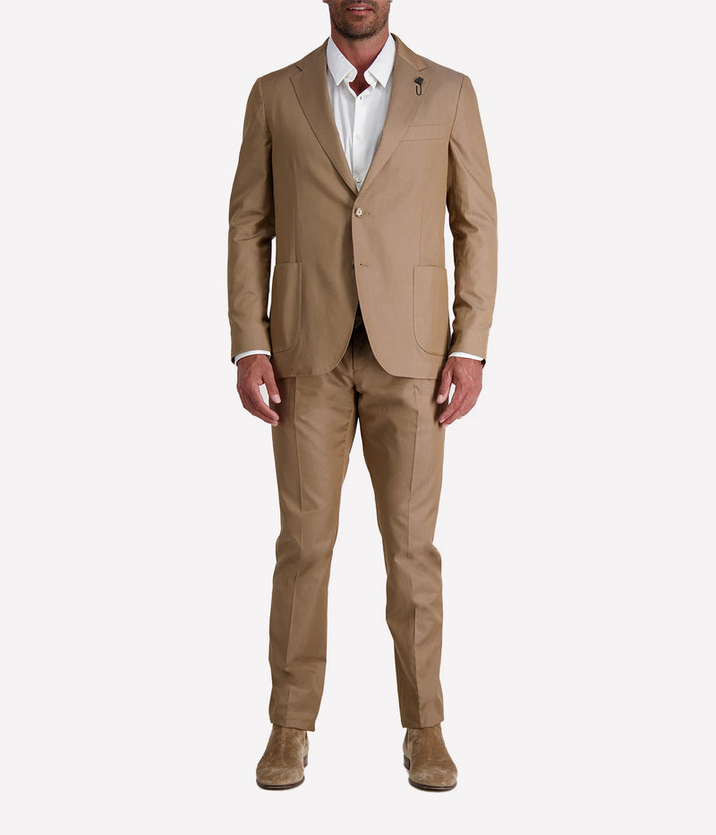 Model wearing a light brown Lardini cotton suit with a white shirt and suede loafers, featuring a single-breasted blazer with Lardini’s signature boutonnière, styled outdoors in a relaxed, modern setting.