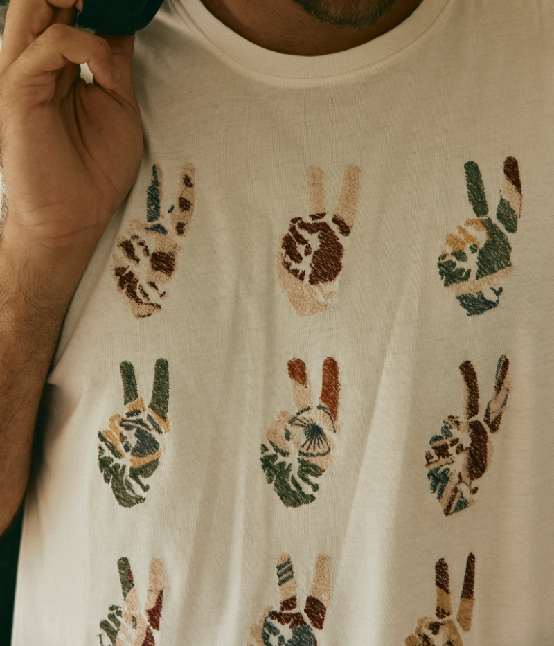 Men's Peace Symbol Graphic Tee in soft cotton with hand-embroidered international flag motifs on the front; features a crewneck and lived-in feel for effortless everyday style.