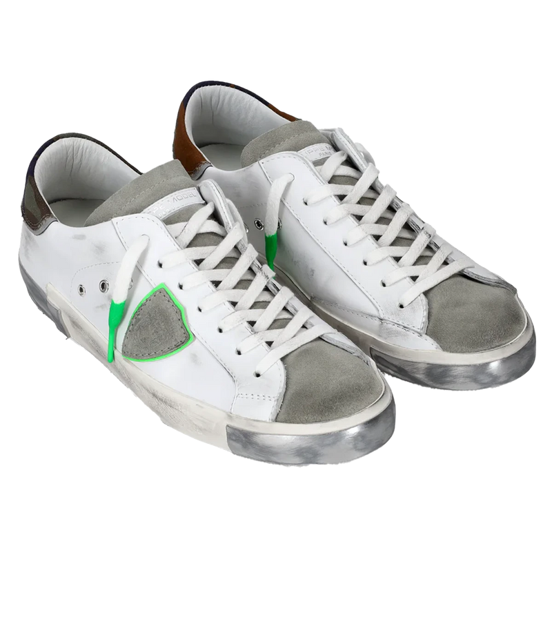 Angle view of Philippe Model PRSX Low Man sneakers, emphasizing the shield on the side of the shoe with the City of Paris coat of arms. The calfskin and suede upper has a worn, vintage-used effect, and the screen-printed laces add to the sneakers' timeless appeal.
