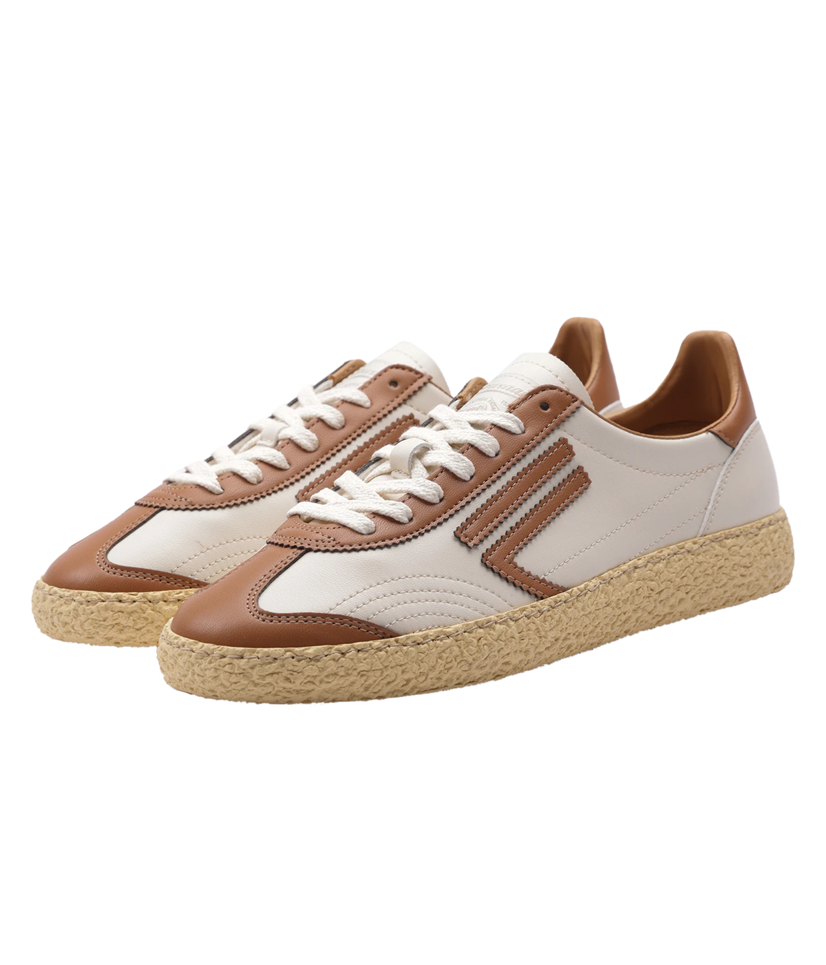 A pair of low-top sneakers with cream and brown panels, white laces, and textured beige espadrille-style soles, shown on a plain white background.