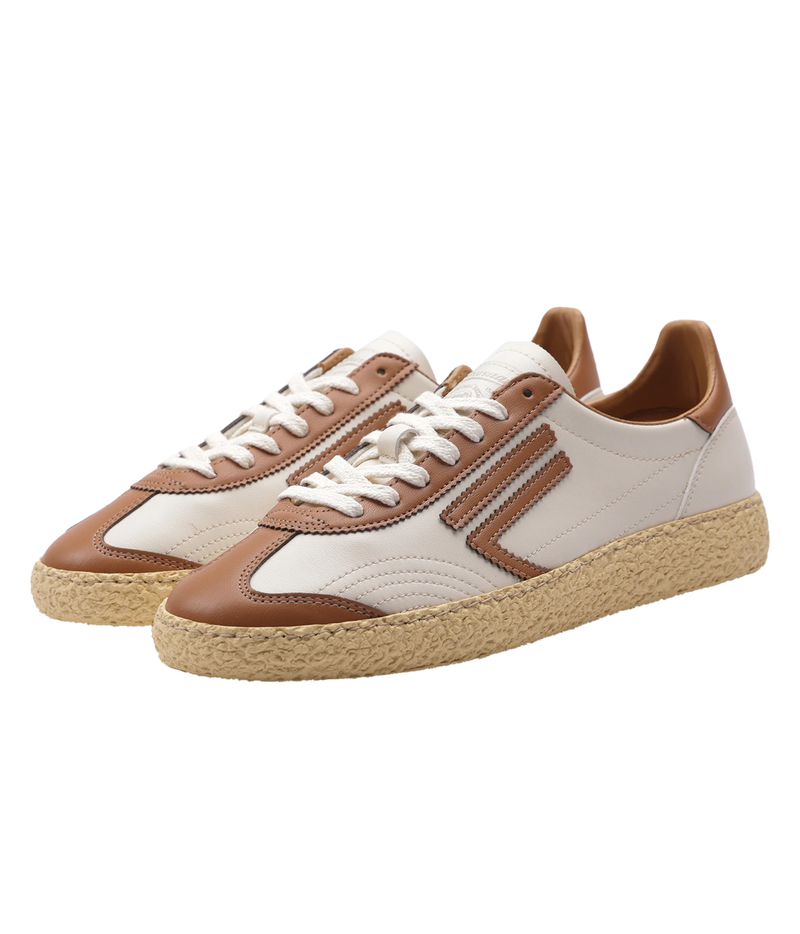 A pair of low-top sneakers with cream and brown panels, white laces, and textured beige espadrille-style soles, shown on a plain white background.