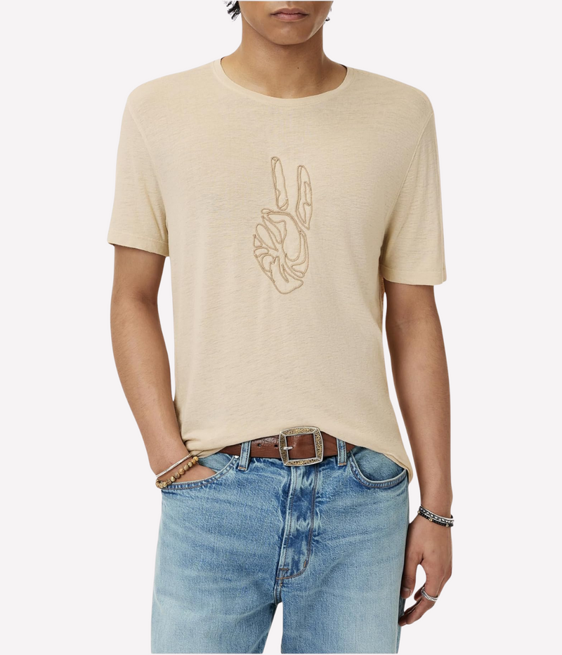 Person wearing a beige t-shirt with a peace sign design and light blue jeans on a white background