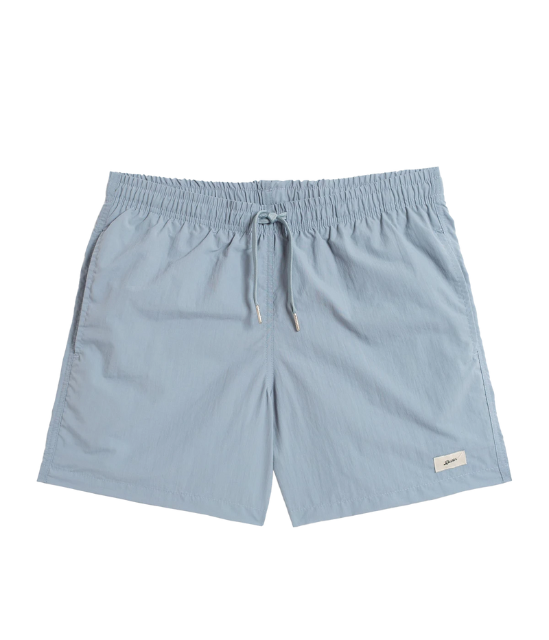 Front view of Bather solid swim trunks, featuring a 5.5-inch inseam and an elasticized waist for a secure and comfortable fit. Made from 100% recycled quick-dry polyester, the trunks are designed with reinforced side pockets and a back pocket with a snap closure.