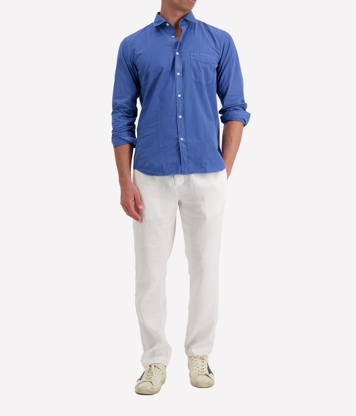 Model wearing the Hartford Storm Pat Shirt in garment-dyed cotton twill, styled with classic linen pants and sneakers. The slim-fit shirt, with a soft collar and chest pocket, strikes the perfect balance between casual ease and refined style.
