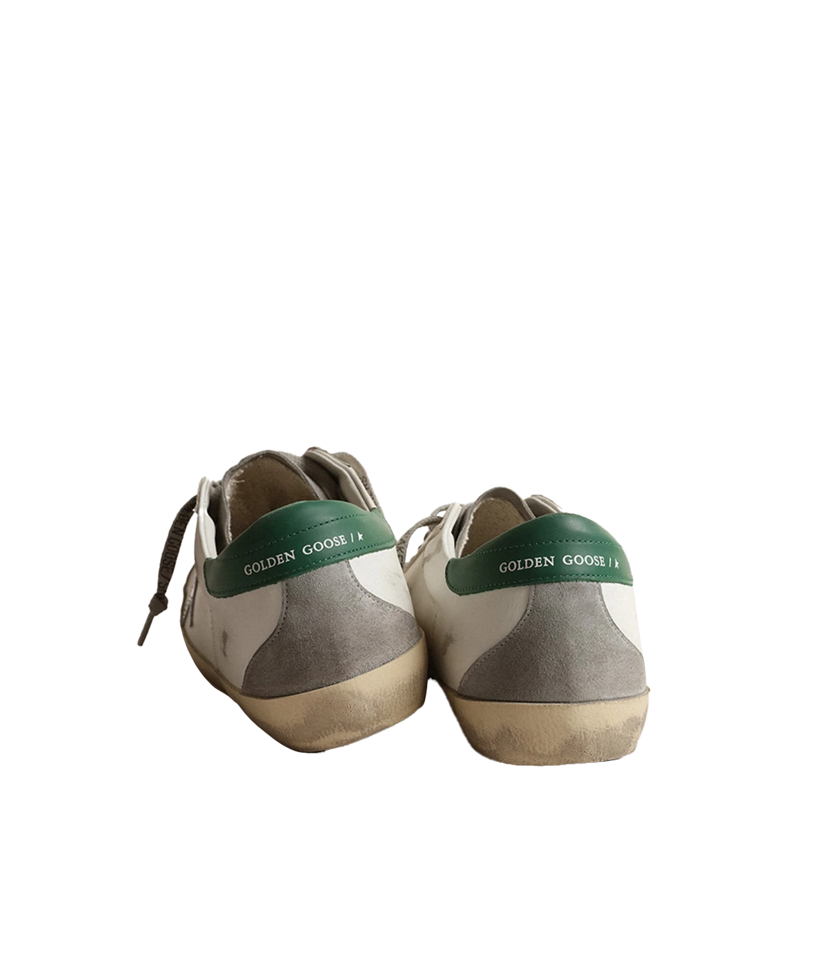 A pair of Golden Goose Super Star Sneakers featuring white calf leather with grey, silver, and green accents. The sneakers have a silver-tone logo print on the side, a signature suede star patch, and a contrasting branded heel counter. Finished with a front lace-up fastening, round toe, and flat rubber sole for added comfort and durability. The design is sleek and modern, making it ideal for casual, everyday wear.