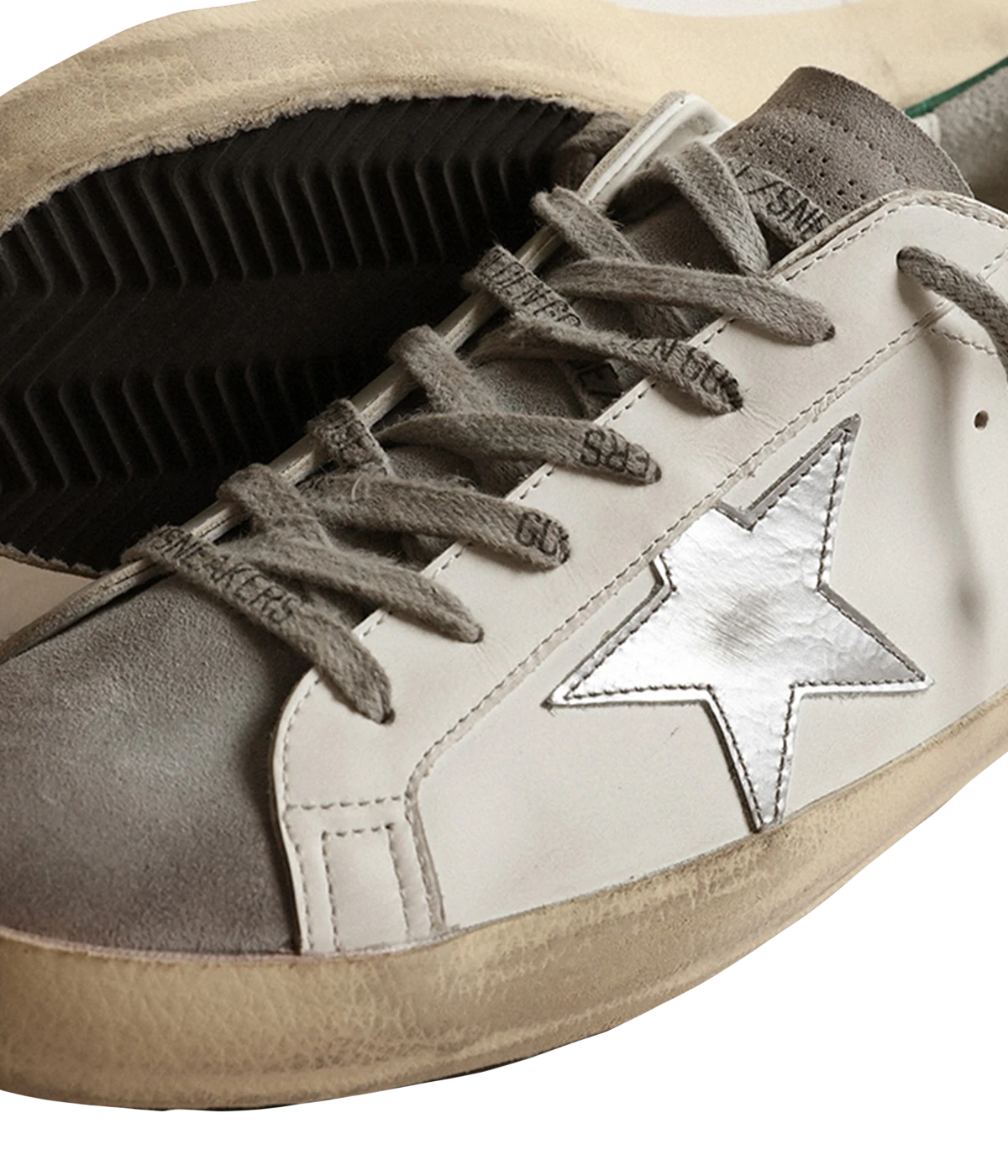 A pair of Golden Goose Super Star Sneakers featuring white calf leather with grey, silver, and green accents. The sneakers have a silver-tone logo print on the side, a signature suede star patch, and a contrasting branded heel counter. Finished with a front lace-up fastening, round toe, and flat rubber sole for added comfort and durability. The design is sleek and modern, making it ideal for casual, everyday wear.