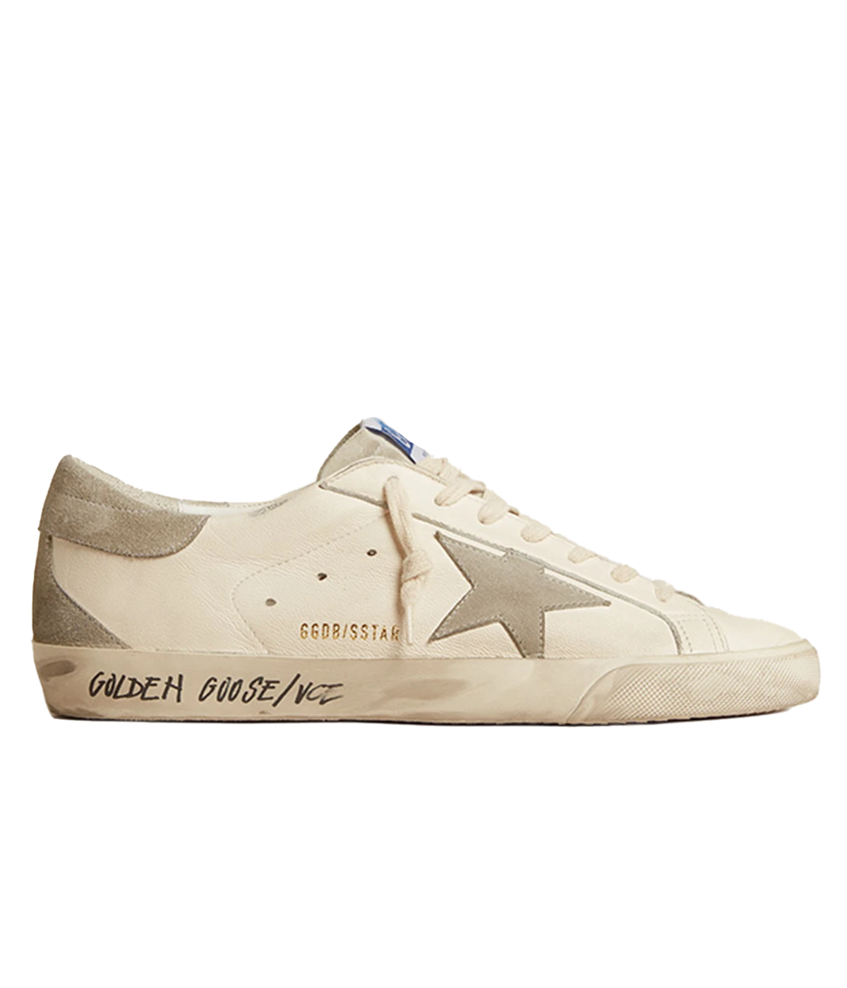 A pair of Golden Goose Super Star Sneakers in off-white calf leather with grey accents. The sneakers feature perforated detailing, a signature suede star patch on the sides, and a logo patch at the tongue. The contrasting grey branded heel counter adds an extra touch of style. Designed with a front lace-up fastening, round toe, and flat rubber sole for comfort and durability, these sneakers are perfect for casual everyday wear.