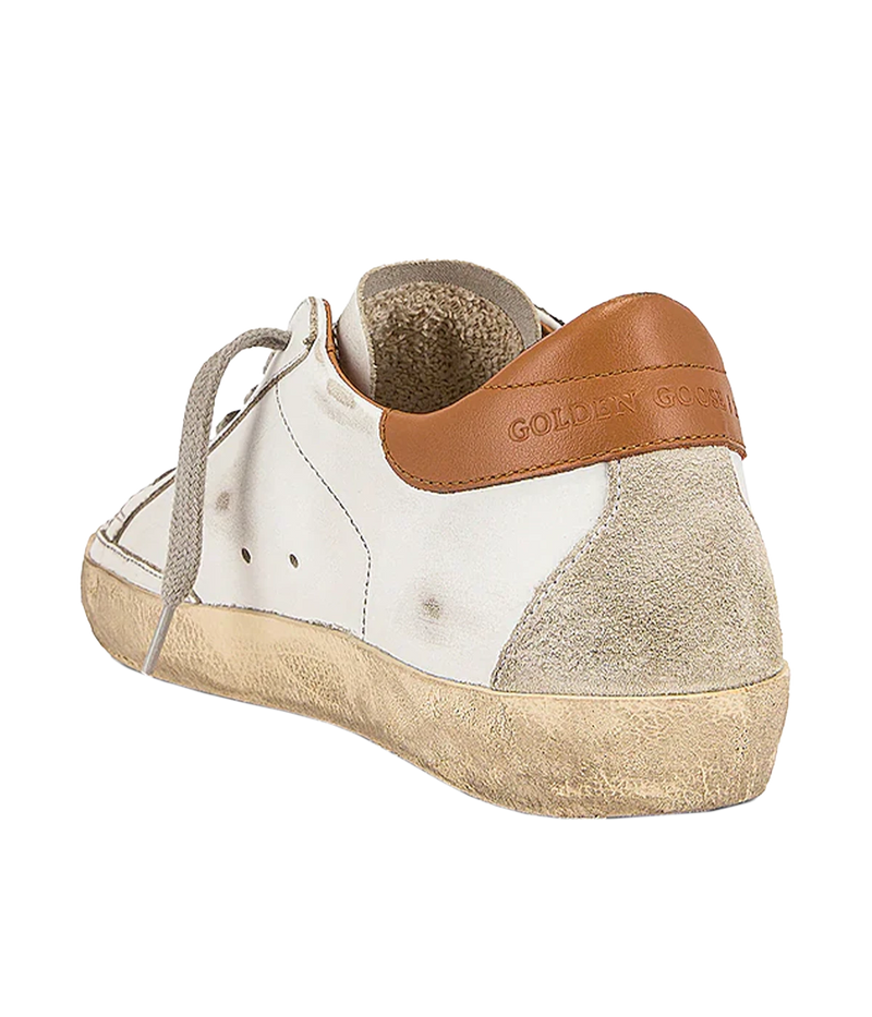 The Golden Goose Super-Star Sneakers in White, Ice & Light Brown feature leather uppers with a distressed finish for a vintage-inspired look. A brown accent at the heel adds a stylish touch, while the iconic star motif on the side wall stands out. With a rubber sole and round toe, these sneakers combine effortless style and comfort, making them a versatile addition to any casual wardrobe.