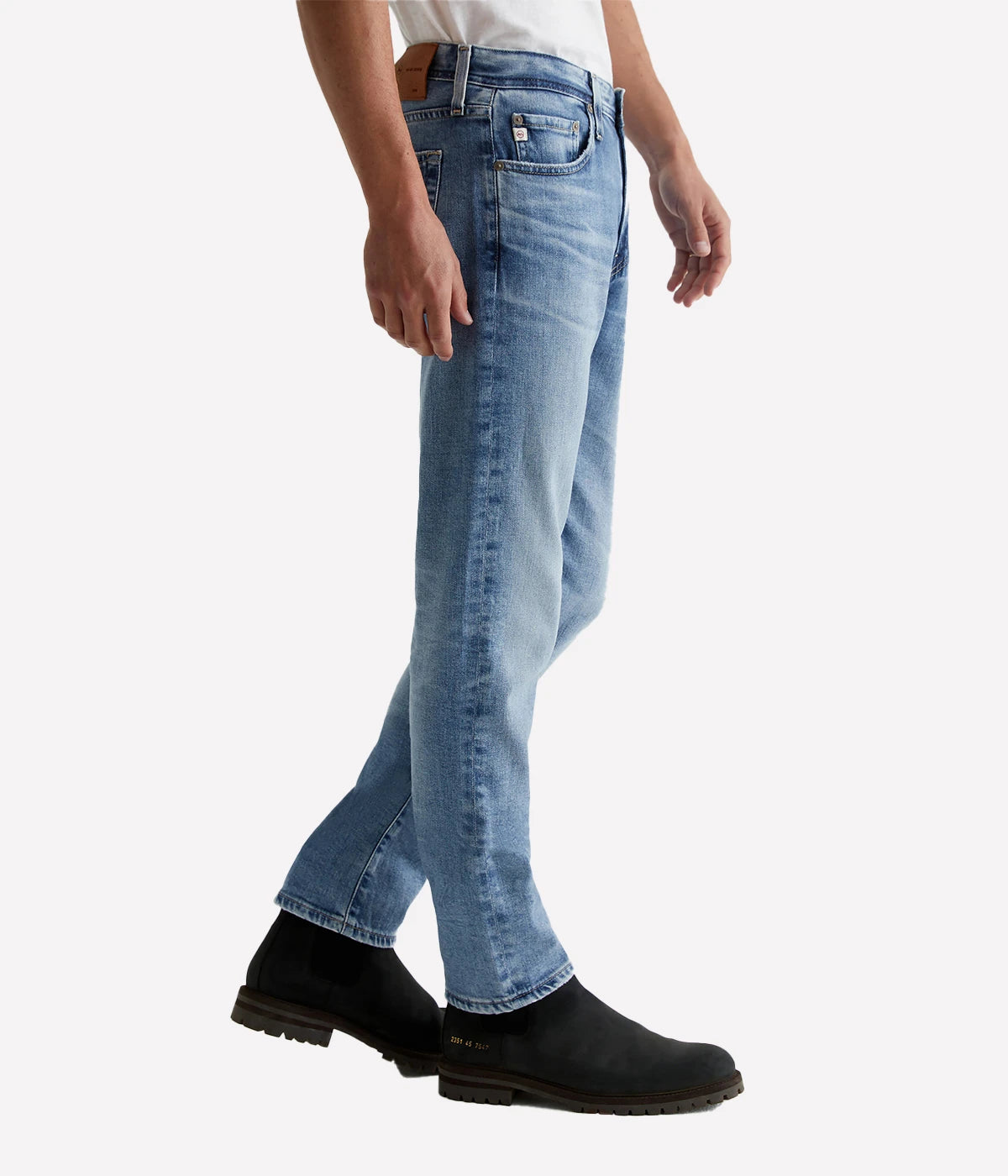 Side view of the Tellis Modern Slim Jean in medium blue wash, emphasizing the fitted upper block and tapered leg opening. The natural whiskering and crease marks add a timeless, lived-in vibe to the modern slim fit.
