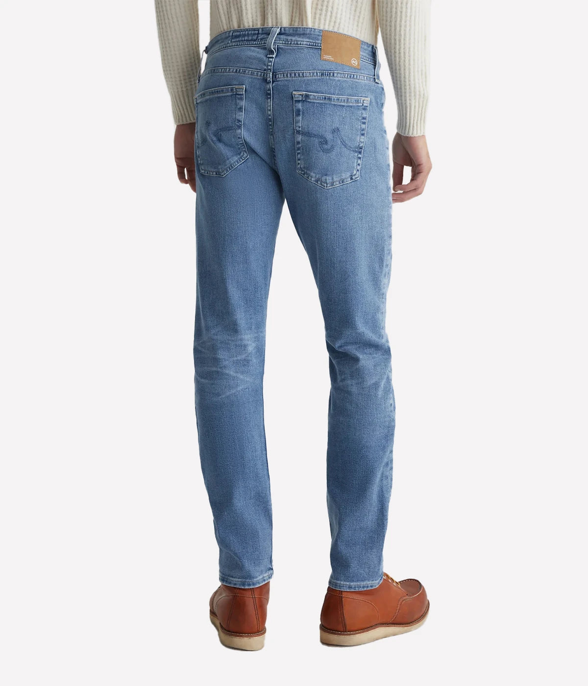 AG Tellis slim-fit jeans for men in a 16-year AG-ed™ light blue, featuring tapered leg opening and fitted upper block. Crafted from 9.4 oz. Hyper Soft Indigo Denim with AG's Cloud Soft Denim™ and dual-elastic performance fibres for a soft, stretchy feel