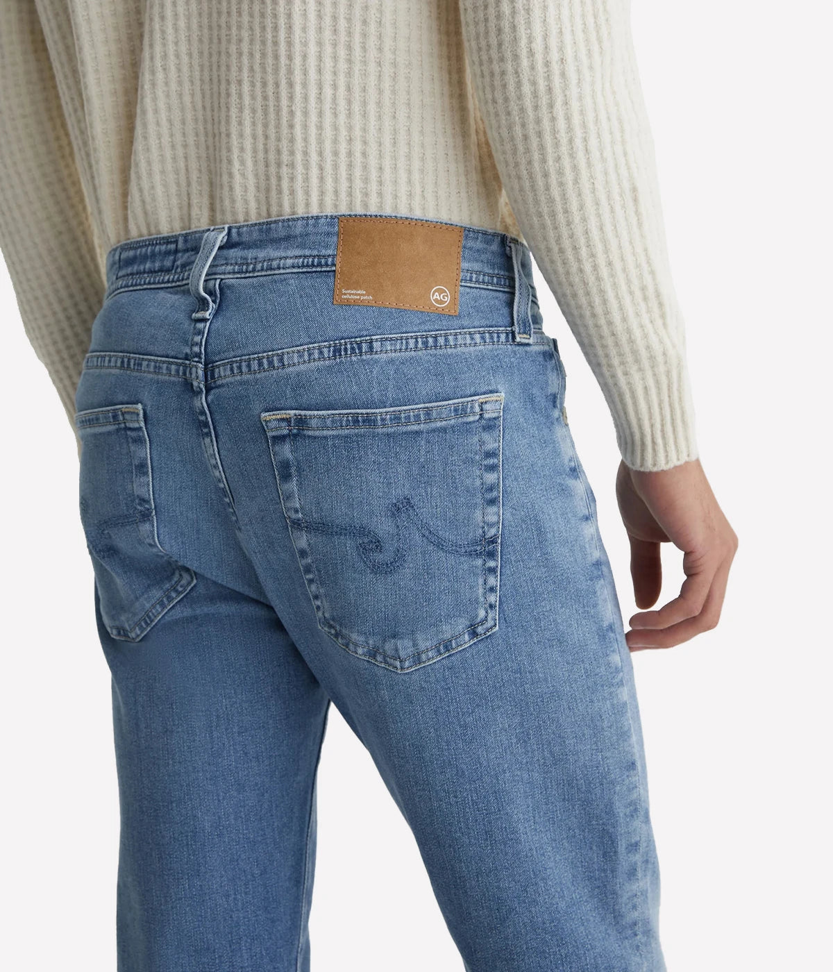 AG Tellis slim-fit jeans for men in a 16-year AG-ed™ light blue, featuring tapered leg opening and fitted upper block. Crafted from 9.4 oz. Hyper Soft Indigo Denim with AG's Cloud Soft Denim™ and dual-elastic performance fibres for a soft, stretchy feel