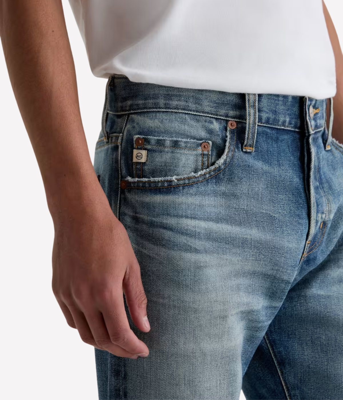 Men’s AG Tellis jeans in 14-year faded blue AG-ed™ wash, crafted from Japanese stretch selvage denim with a modern slim fit and tapered leg.