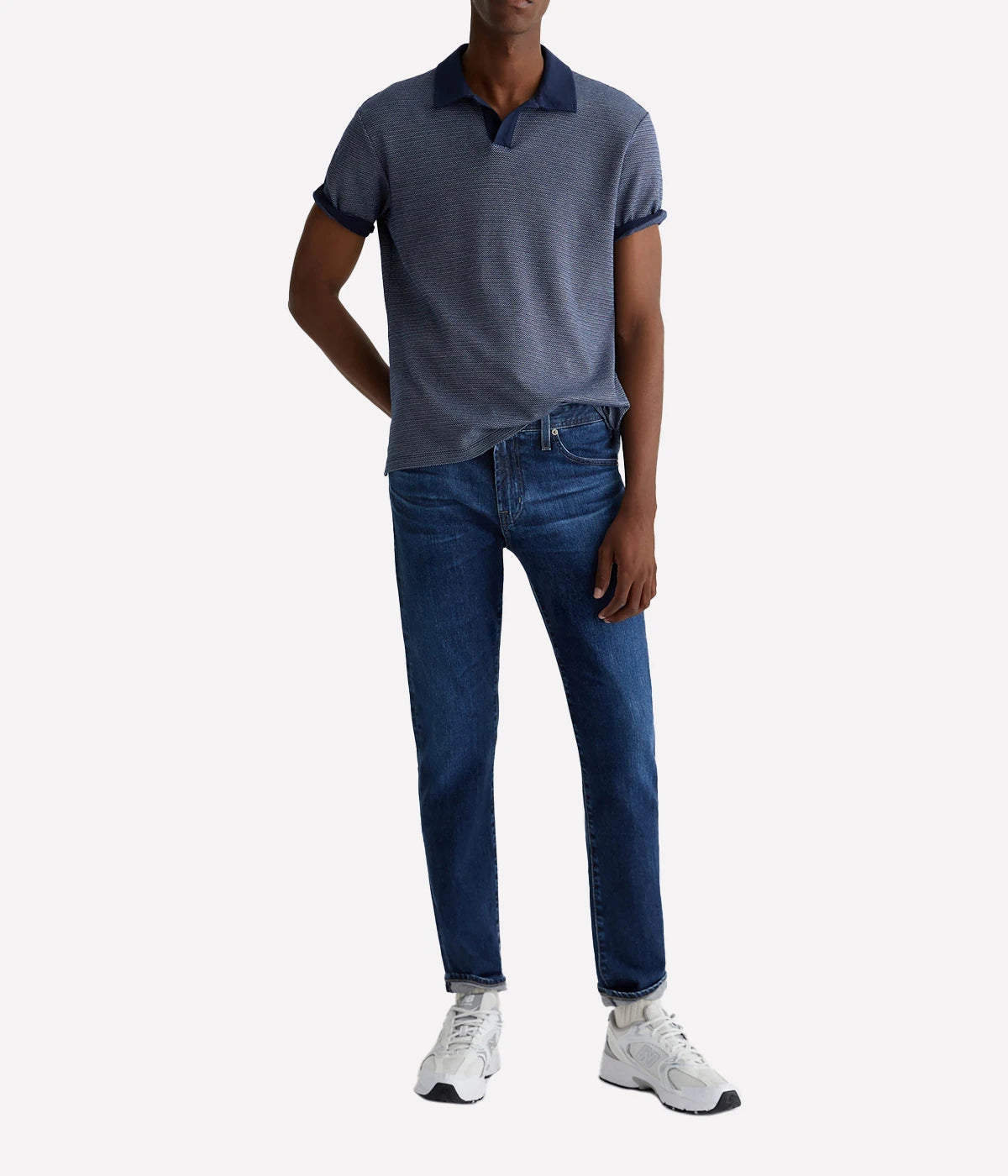 AG Tellis Modern Slim Jeans for men in a medium indigo wash, created using eco-friendly AG Vapor Wash™ technology for a sustainable finish. Designed with a fitted upper block and tapered leg opening, these jeans are crafted from 11 oz. Lead Denim with comfortable stretch. Complete with a vegan, biodegradable cellulose patch at the back waistband for a conscious style choice.