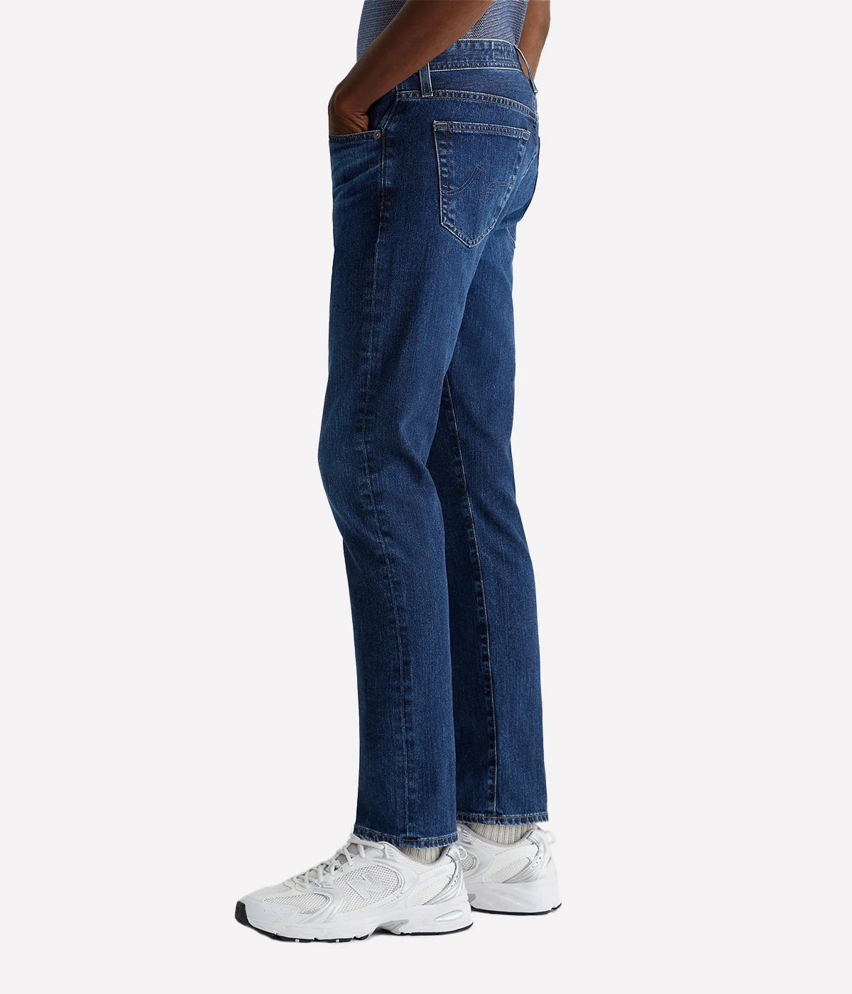 AG Tellis Modern Slim Jeans for men in a medium indigo wash, created using eco-friendly AG Vapor Wash™ technology for a sustainable finish. Designed with a fitted upper block and tapered leg opening, these jeans are crafted from 11 oz. Lead Denim with comfortable stretch. Complete with a vegan, biodegradable cellulose patch at the back waistband for a conscious style choice.