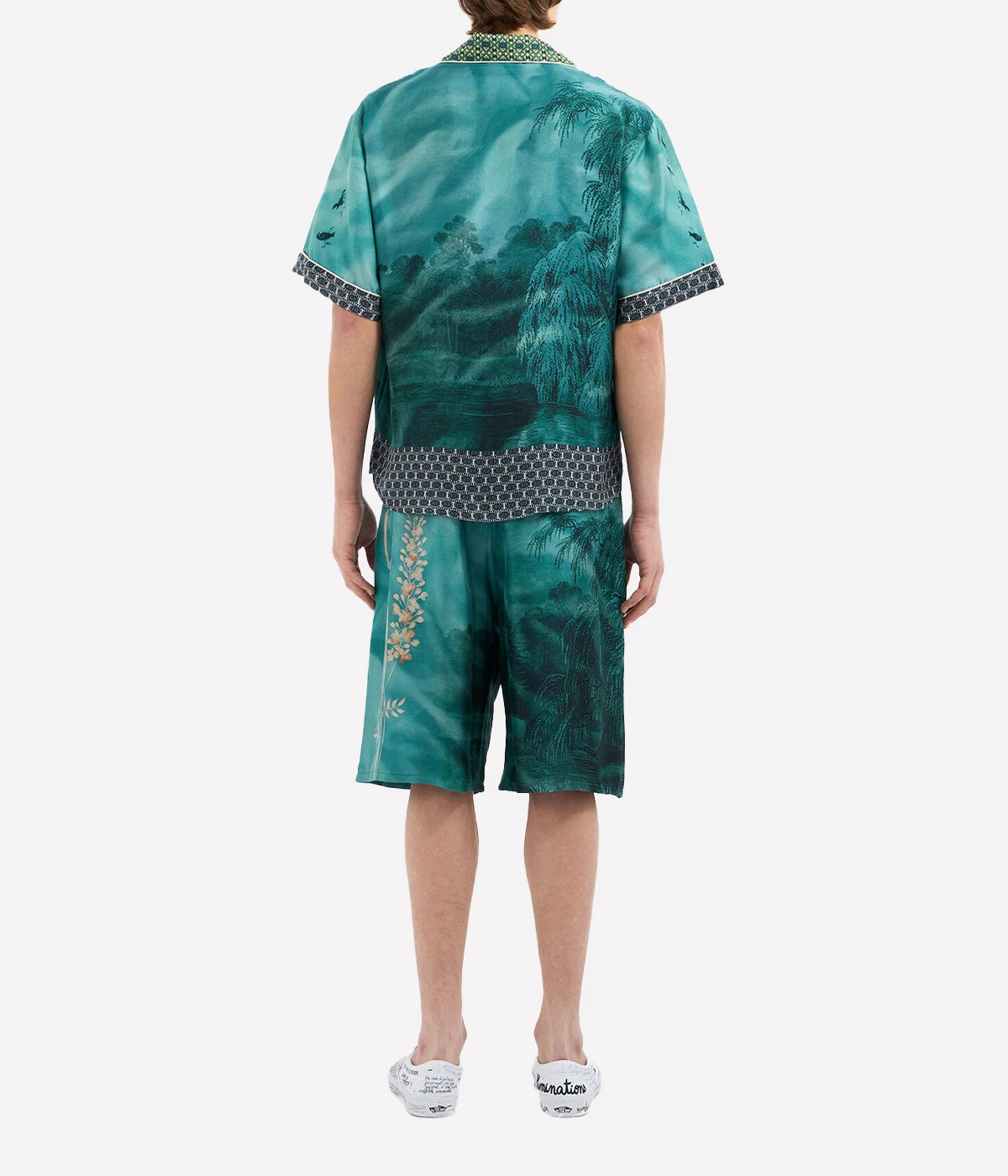 Short-sleeved silk shirt with teal landscape, botanical, and bird motifs, open collar, and button front.