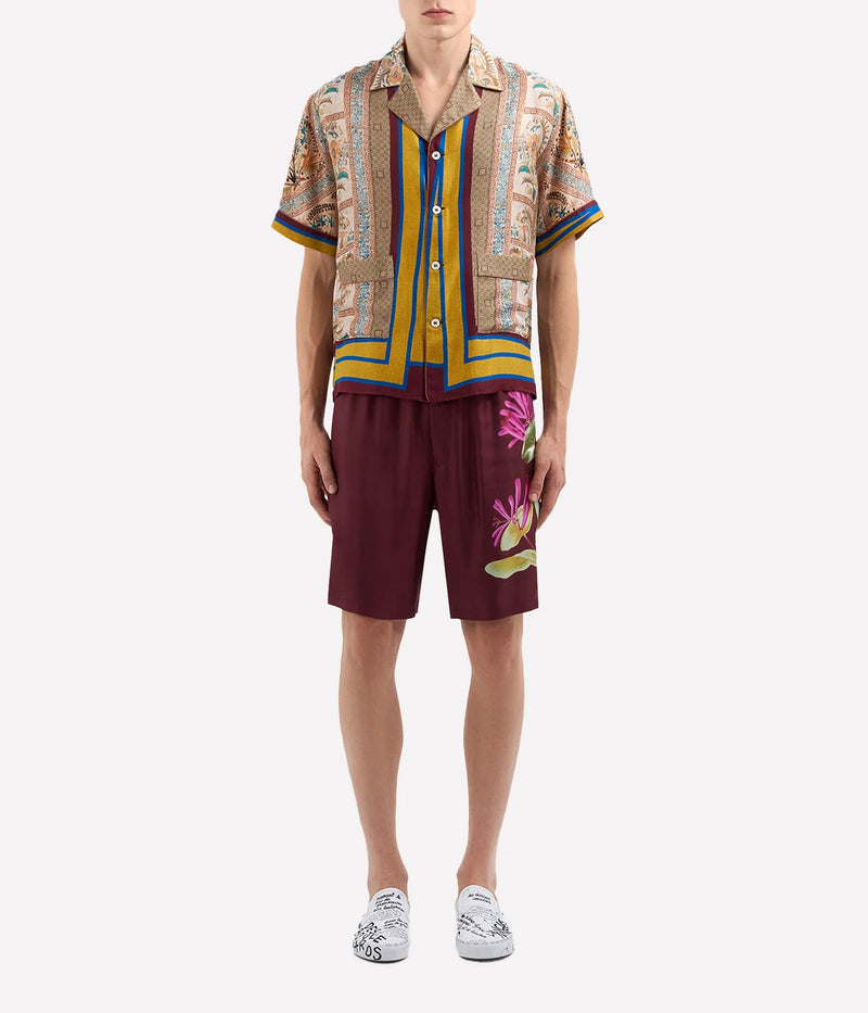 Warm-toned geometric print silk shirt with pops of blue and yellow, notched collar, and short sleeves.