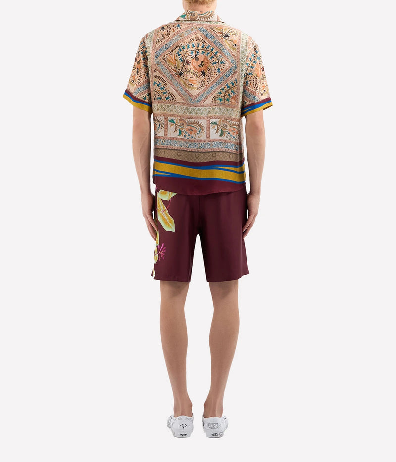 Warm-toned geometric print silk shirt with pops of blue and yellow, notched collar, and short sleeves.