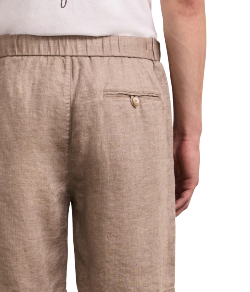 Close-up of beige pants with a button on a white background