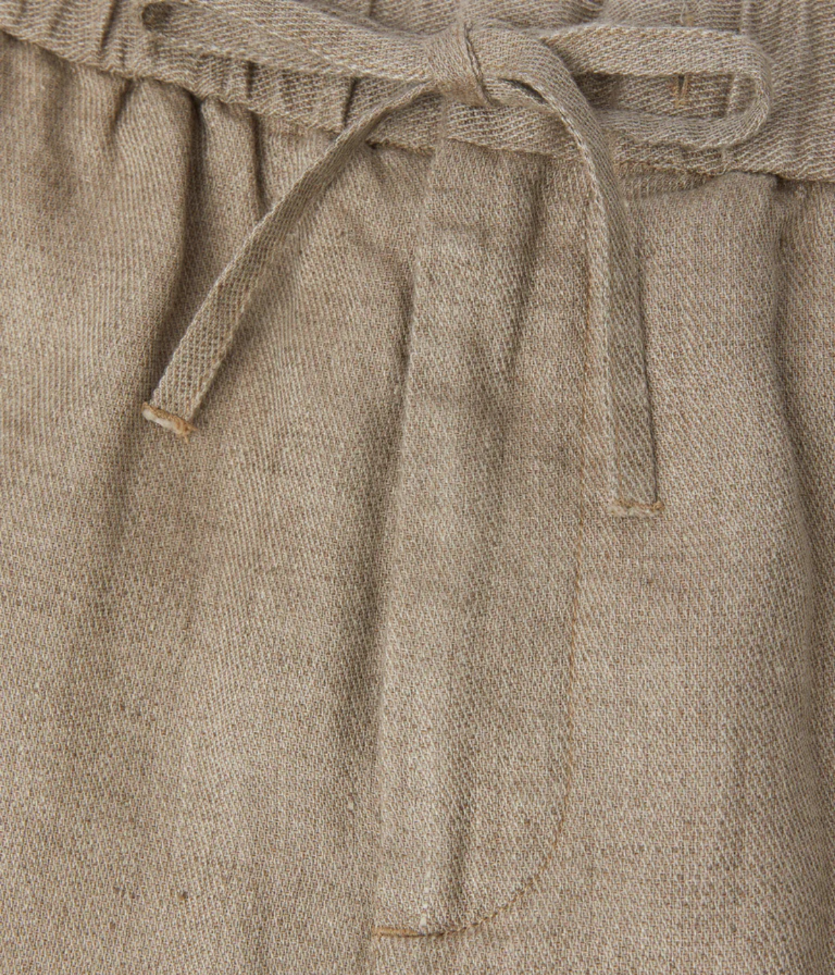 Close-up of beige pants with a tie waist