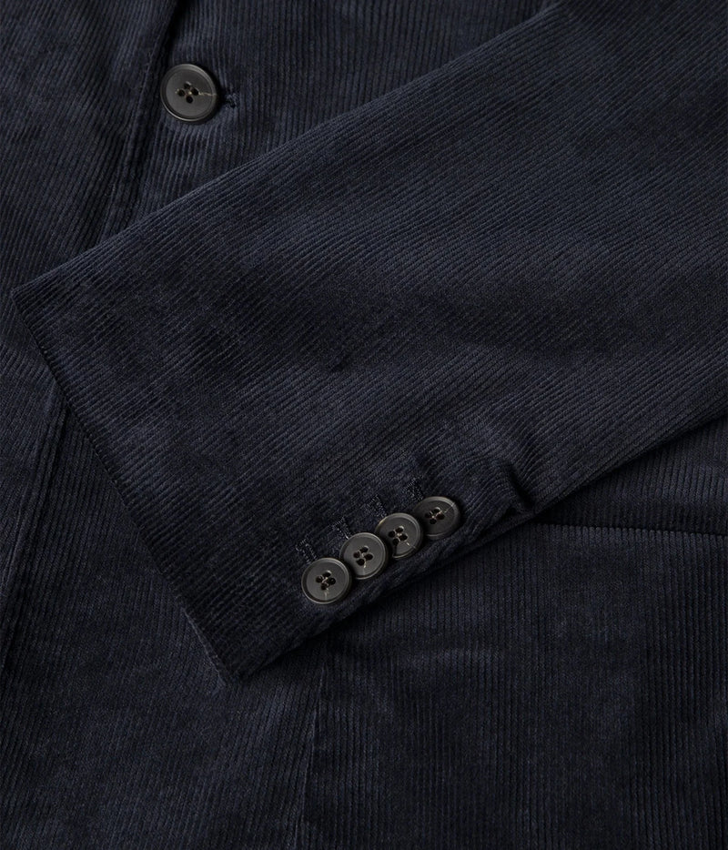 Close-up of a dark navy corduroy jacket or blazer showing the textured fabric, a button placket, and the cuff with four buttons.