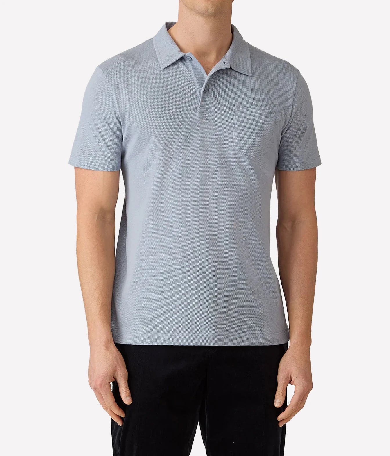 A man wearing a light gray short-sleeve polo shirt with a chest pocket, paired with black pants, shown against a plain light gray background.