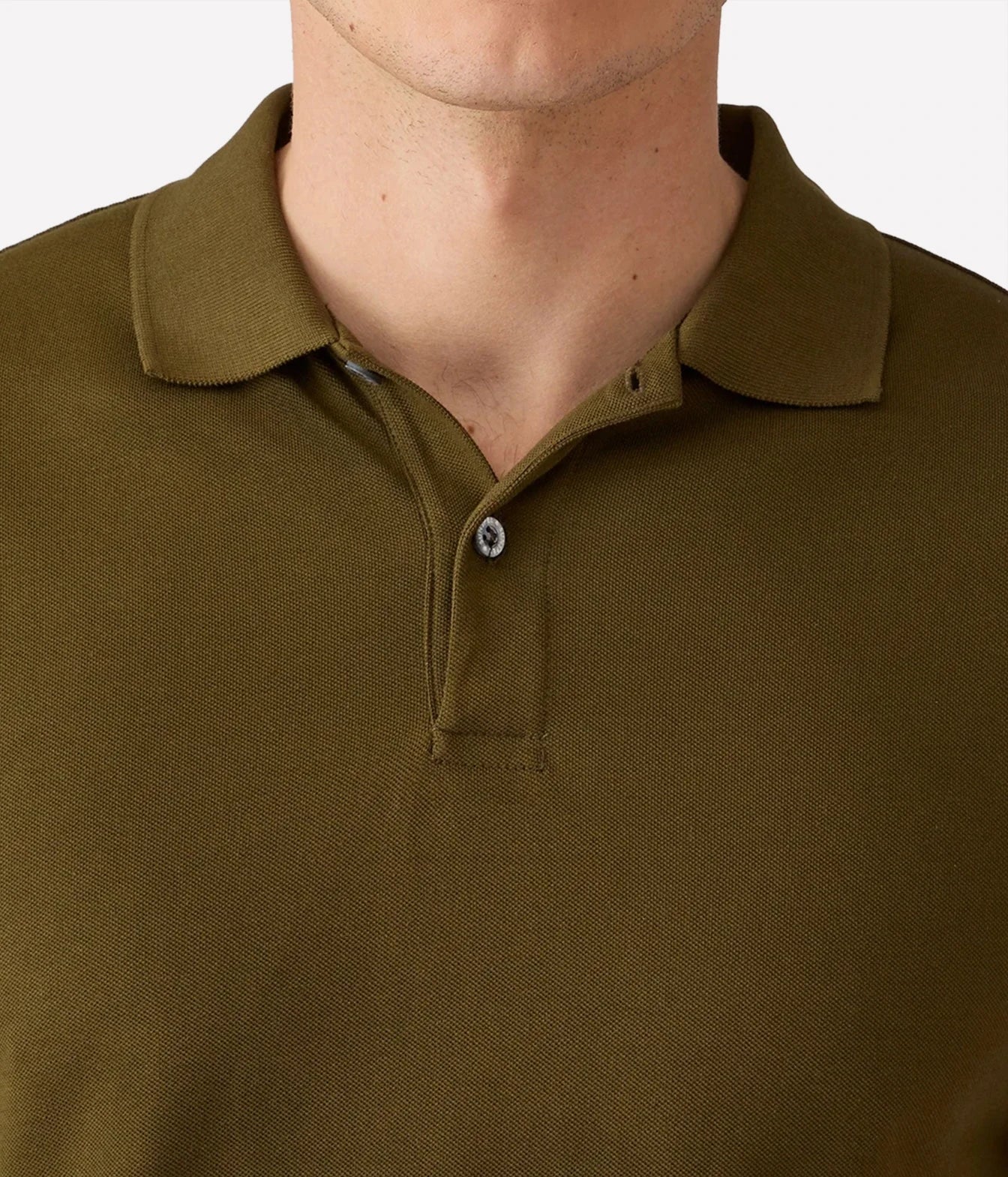 Close-up of a man wearing an olive green polo shirt, showing the collar, button placket, and textured fabric.