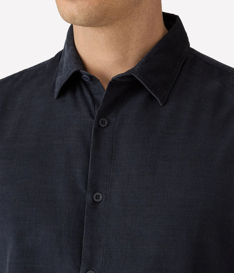 Close-up of a man wearing a dark navy blue linen button-down shirt, showing the collar, buttons, and textured fabric.
